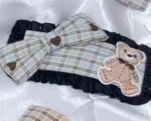 Detail of green plaid headband featuring a fabric bow, bear patch and pleated lace trim