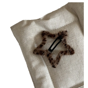 Star-shaped plush leopard print BB hair clip with soft faux fur on a beige texture mat
