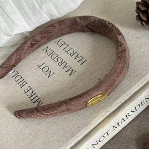 Macro detail of brown textured scrunchie with a gold 'Handmade' tag on vintage books
