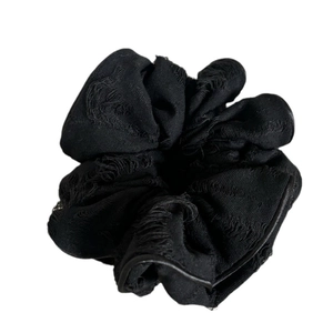Distressed black scrunchie with frayed edges for a minimalist vintage aesthetic