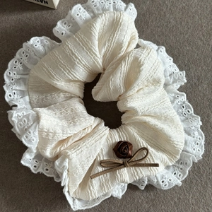 Close-up of cream lace scrunchie with brown rose and bow detail on grey felt surface
