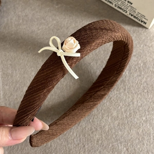 Close-up of brown crepe headband with cream satin rose and ribbon bow detail
