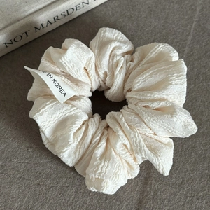 Detail of off-white oversized scrunchie featuring textured crinkle fabric and woven label