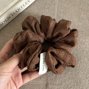 Detail of a brown bubble textured scrunchie with a handmade woven label and soft fabric