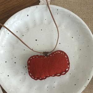 Vue détaillée d'un pendentif pomme fait main en velours côtelé avec des coutures blanches à la main