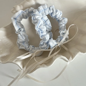 Blue and white striped scrunchie set with cream ribbon bows on a shell display tray