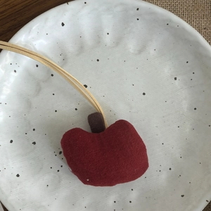 Gros plan détaillé du pendentif pomme en tissu fait main dans une coupelle en céramique