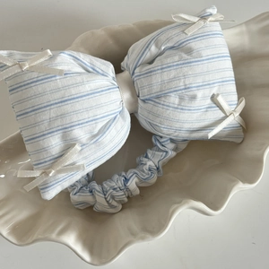 Macro view of blue striped fabric bow headband with small ribbon details in a shell tray