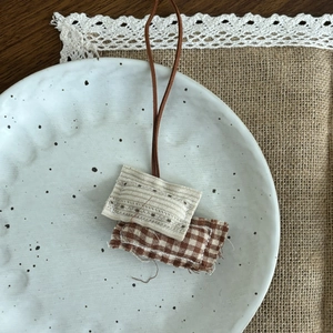 Détail d'un pendentif artisanal en tissu avec broderie sur une assiette en céramique rustique