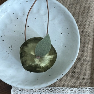 Gros plan sur le pendentif pomme fait main vert foncé avec feuille en feutrine