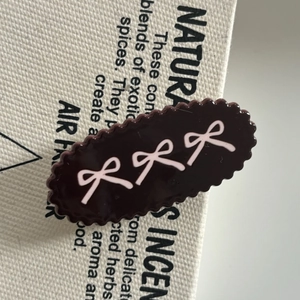 Macro view of brown acrylic hair clip with pink bow patterns and wavy edges