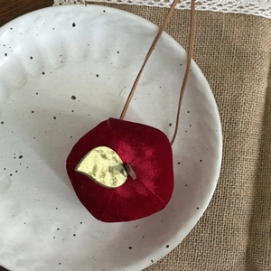 Détail du pendentif pomme en velours rouge fait main sur une assiette en céramique