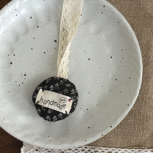 Gros plan d'un pendentif pomme en tissu fait main avec motif floral et ruban dentelle