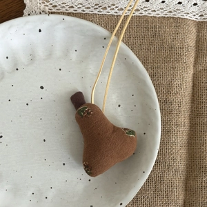 Détail de la broderie sur le pendentif poire en tissu fait main au style rustique