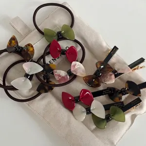 Elegant acetate bow hair clips and elastic hair ties in multiple colors on a linen bag