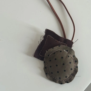 Détail du pendentif en tissu style forêt avec pois verts et textures textiles brunes
