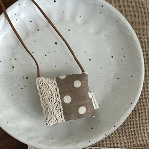 Détail de pochette collier faite main à pois marrons avec dentelle sur une assiette