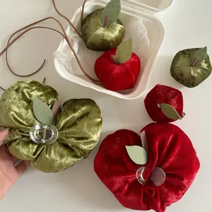 Detail of red velvet apple shark hair clip and decorative pendant with felt leaf accents