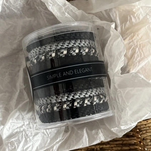 Set of black and gray elastic hair ties stored in a transparent cylindrical gift container