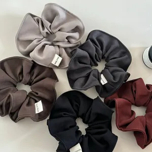 Detail view of five assorted earth-toned fabric scrunchies with Hand Made labels