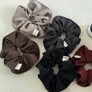 Five-piece set of large fabric scrunchies in neutral tones with hand-made labels