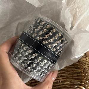 Detailed macro view of black and white braided elastic hair ties in transparent box