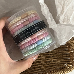 Close-up of colorful thick elastic hair ties in a transparent simple cylinder container