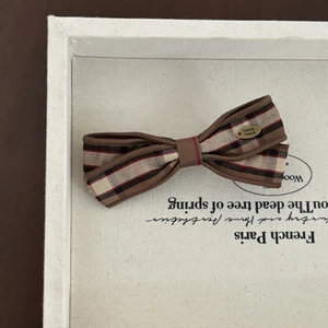 Vintage plaid bow hair clip with 'Hand made' gold charm on white canvas tray