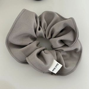 Detail of grey fabric scrunchie with twill texture and handmade woven label tag