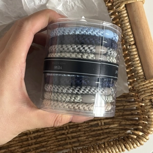 Macro shot of high-elasticity hair ties in a clear cylindrical box with a blue color palette