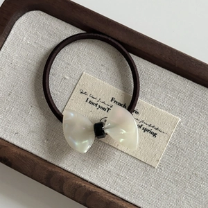 Detail of a French style acetate pearl bow hair tie with a brown high-elastic rubber band