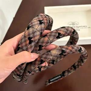 Brown plaid padded headband featuring black bow patterns and handmade fabric texture