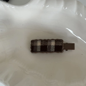 Detail view of a vintage plaid fabric hair clip with a stylish wavy edge frame