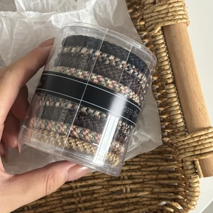 Elastic braided hair ties in various colors neatly stored in a clear cylindrical box