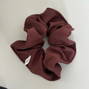 Detail of dark burgundy ribbed fabric scrunchie with a white Hand Made label tag
