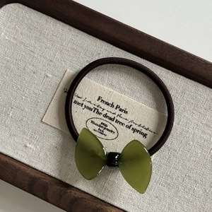 Close-up of a green translucent resin bow hair tie with a high-elasticity brown rope