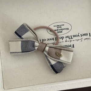 Detailed macro view of checkered bow hair tie with vintage hand made metal charm