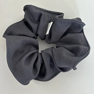 Detail view of dark grey fabric scrunchie texture with high-quality stitching and label
