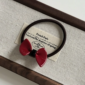 Detail of red acetate bow hair tie on vintage fabric background with French text label