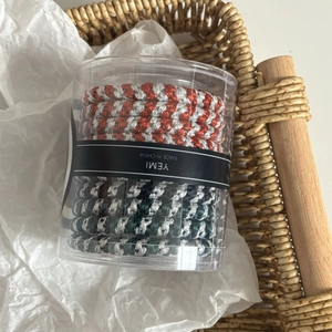 Detail of high-elasticity braided hair ties set in a clear cylinder storage container
