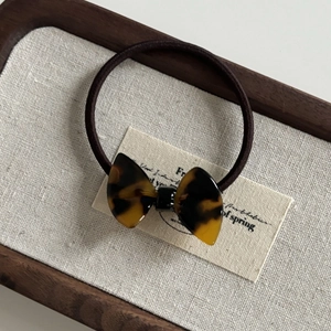 Macro detail of tortoiseshell pattern acetate bow hair tie with brown elastic band