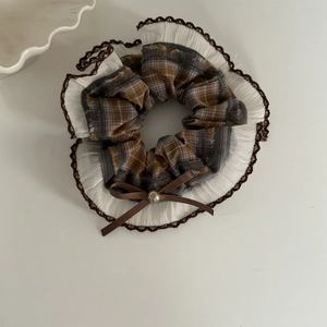 Vintage checkered scrunchie with white lace edges and a brown ribbon bow on white