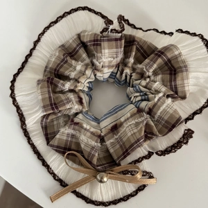 Close-up of vintage plaid hair scrunchie with white pleats, lace trim and a golden bow