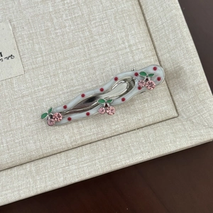 Close-up of wavy cherry hair clip with red polka dots and pink crystal embellishments