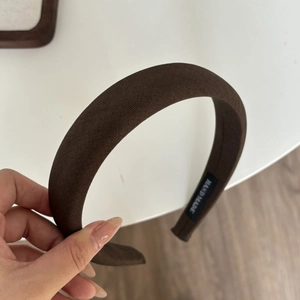 Gros plan d'un serre-tête épais marron foncé fait main avec une texture en tissu