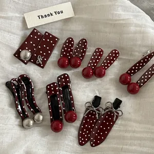 Vintage burgundy hair clips with white polka dots and 3D cherry accents on white fabric
