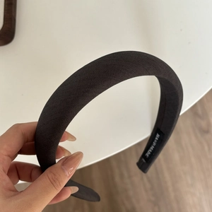 Détail d'un serre-tête éponge marron foncé avec texture tissu et étiquette main