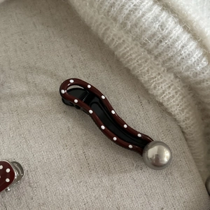 Detail of red polka dot hair clip with wave design and silver bead on soft fabric