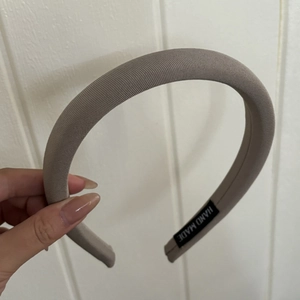 Détail d'un serre-tête en tissu taupe avec une étiquette faite à la main de qualité
