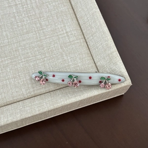 Detailed view of cherry hair clip with pink crystal rhinestones and red polka dots